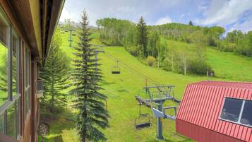 A ski lift, a red building, and a view of a green hillside with trees.