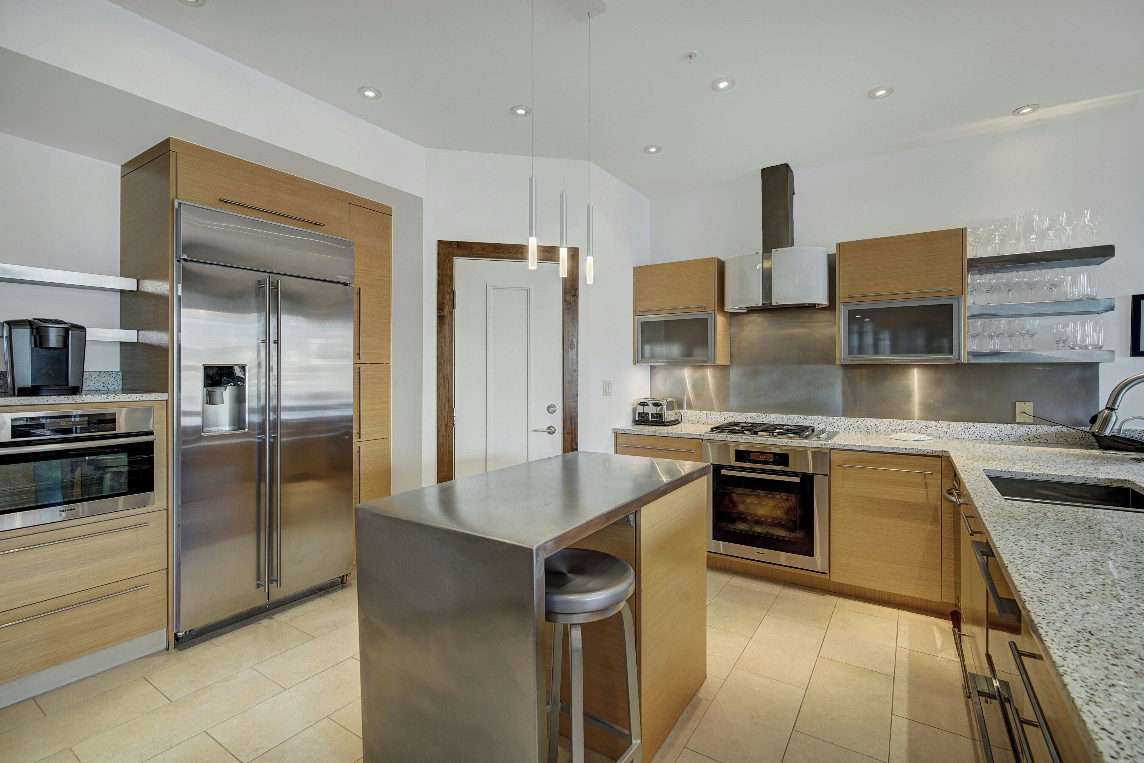 A modern kitchen with stainless steel appliances, wooden cabinets, and a granite countertop.