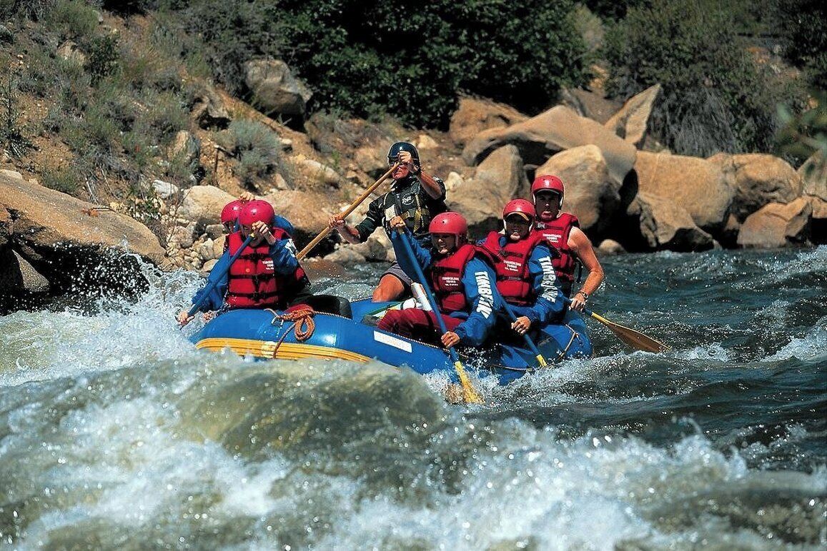 Un groupe de personnes à bord d’un radeau bleu naviguant sur une rivière.