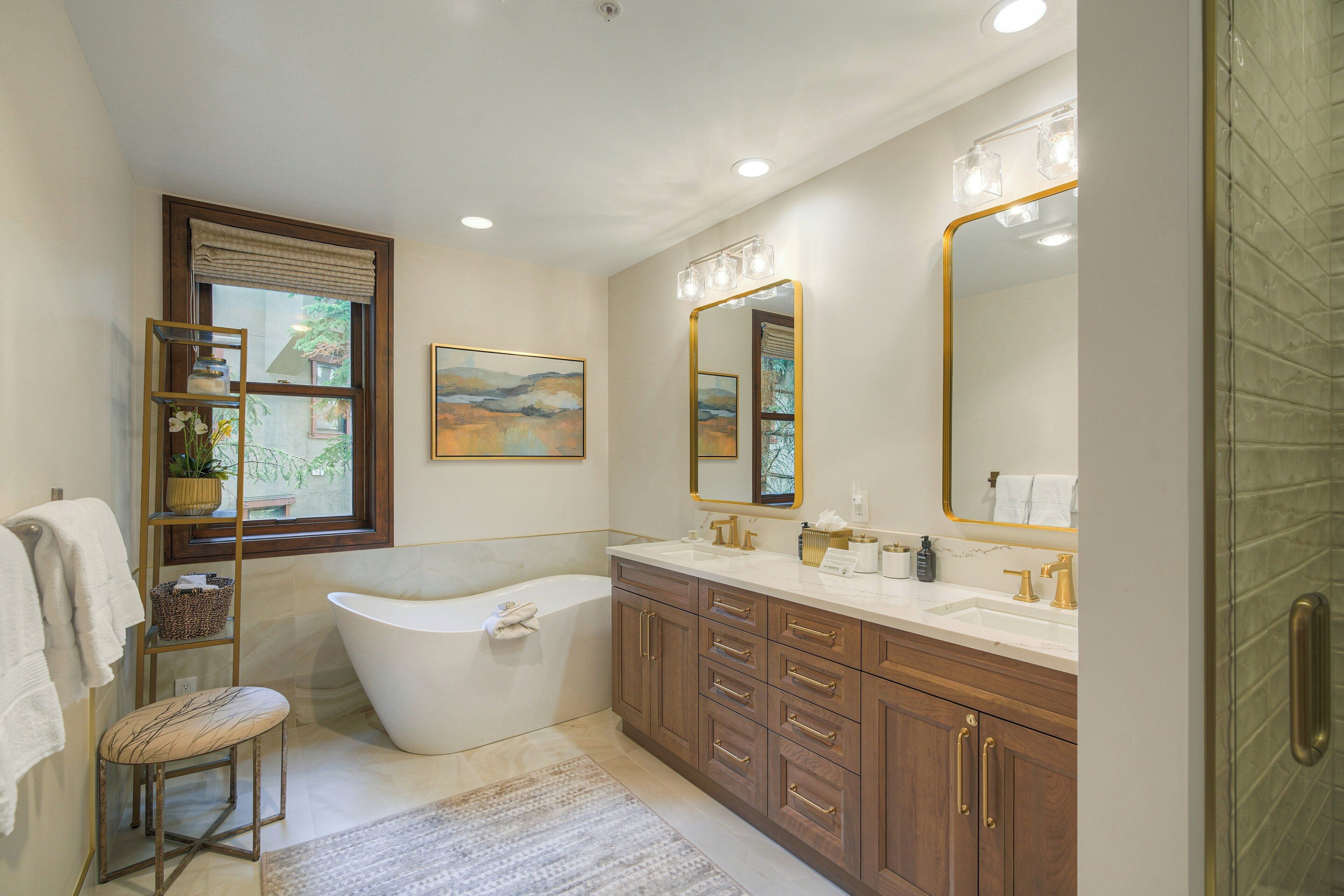 A modern bathroom with a freestanding bathtub, a vanity with dual sinks, and a large mirror.