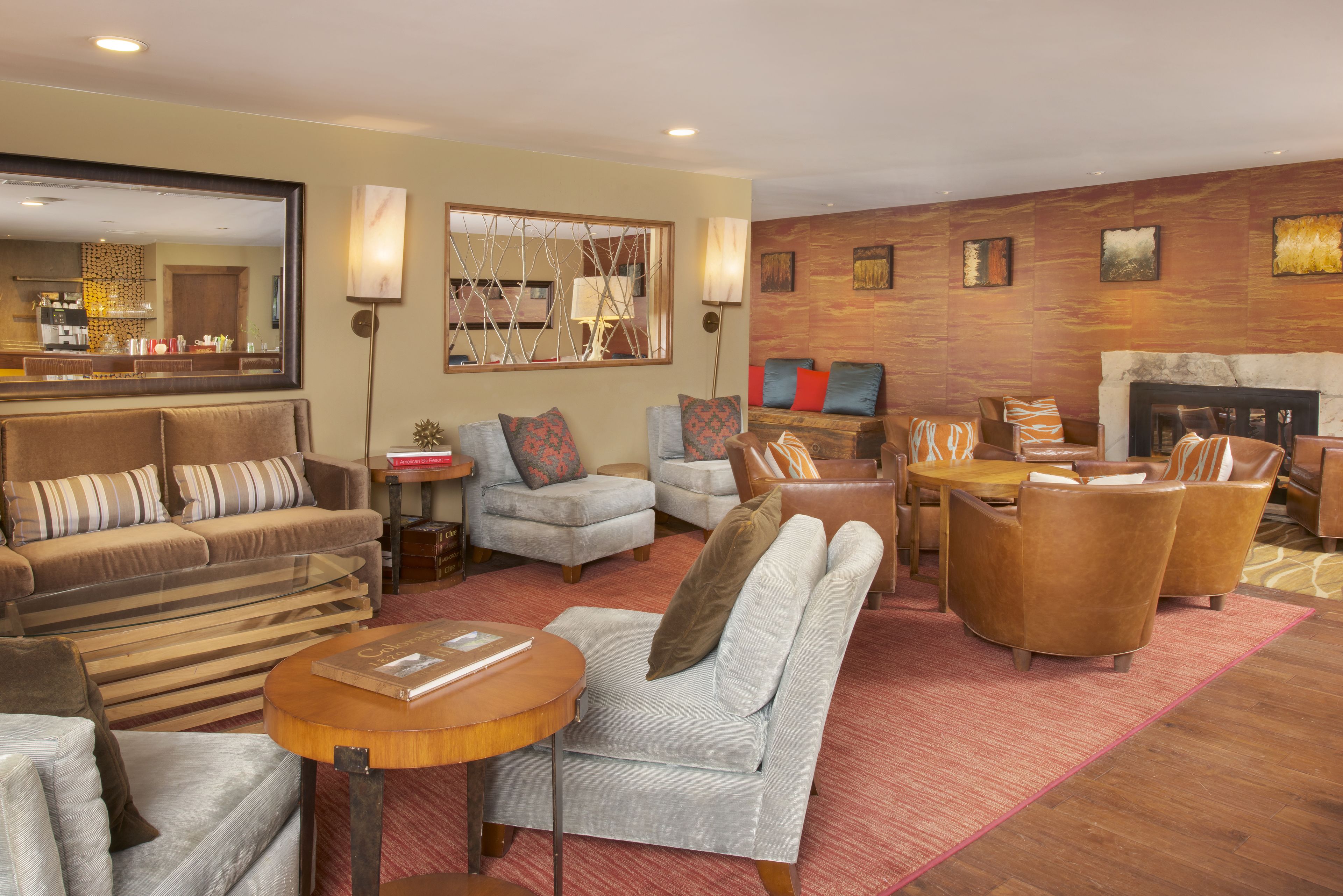 A spacious living room with a fireplace, comfortable seating, and a large mirror.