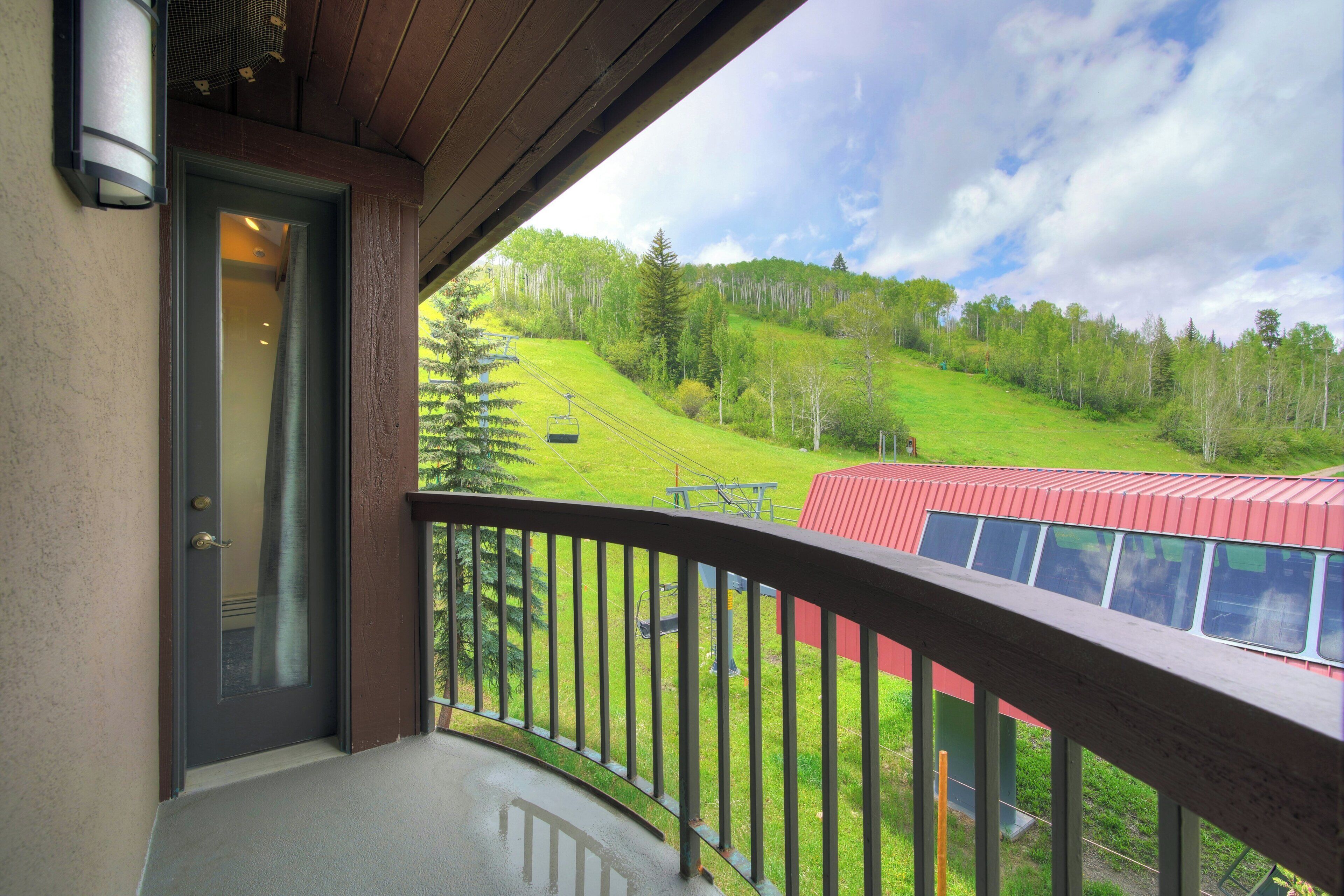 A balcony with a view of a green landscape and a red building.