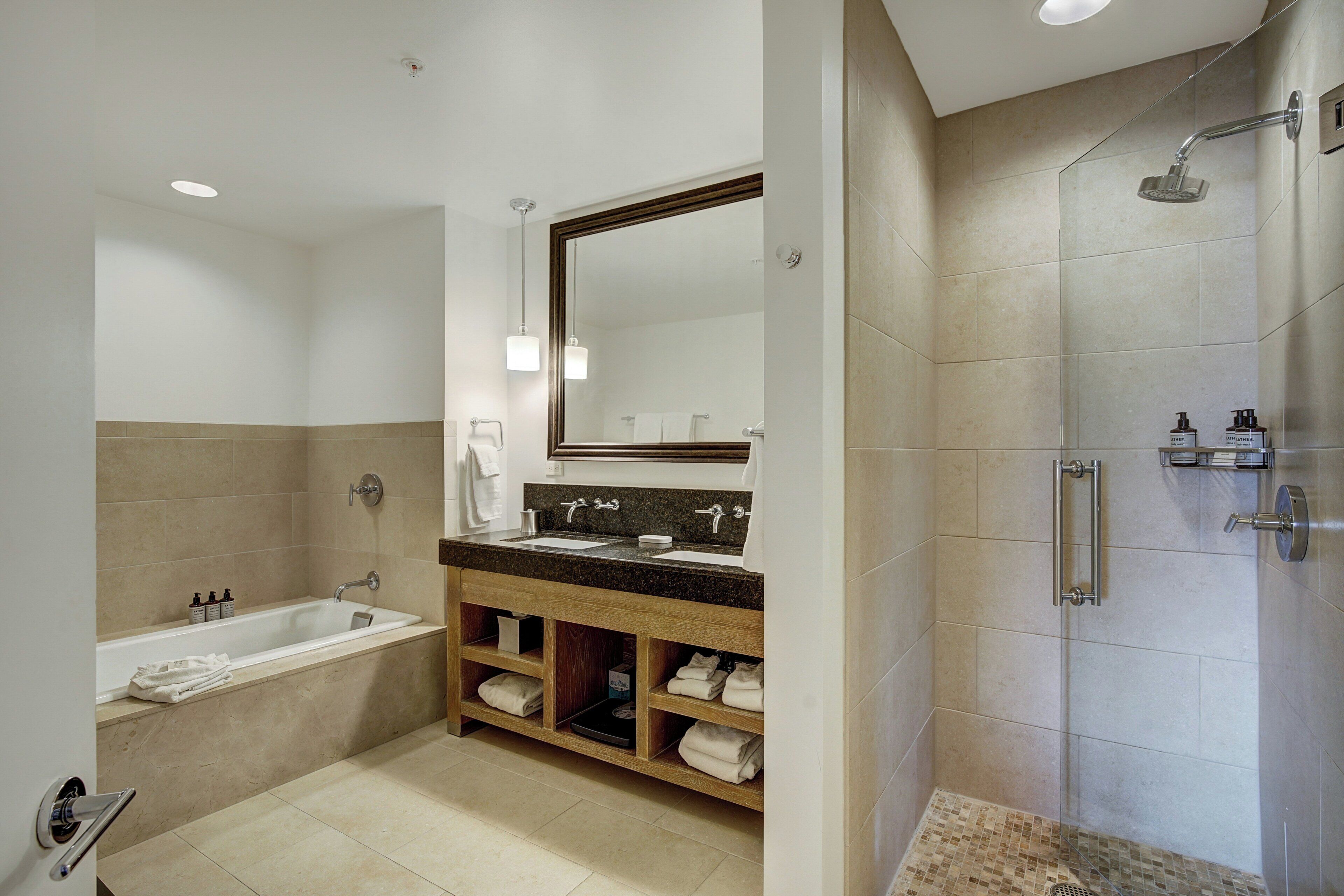 Un baño moderno con bañera, ducha, tocador con espejo y estantes empotrados para toallas.