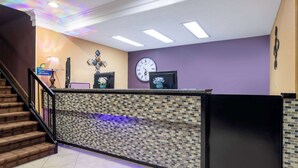A reception area with a tiled counter, a clock, and a staircase. - Days Inn by Wyndham Anderson IN (Anderson)