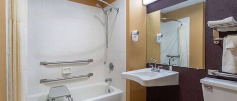 A bathroom with a bathtub, a sink, and a toilet. There are grab bars in the shower, and a step stool is placed inside the tub.