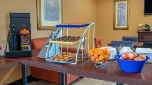 A breakfast buffet with muffins, cookies, oranges, and apples. - Days Inn by Wyndham Anderson IN (Anderson)