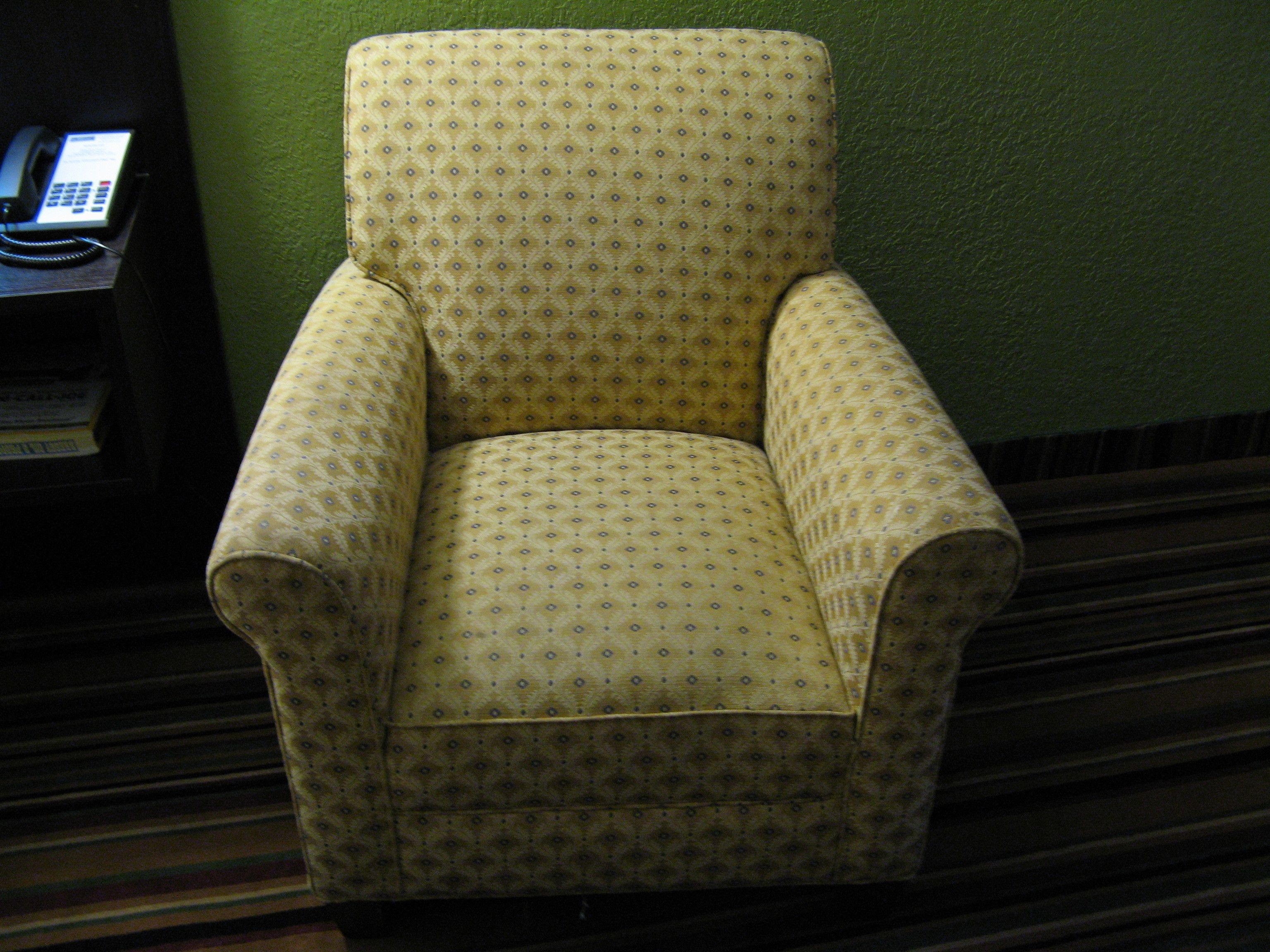Un sillón amarillo con un estampado de diamantes frente a una pared verde.