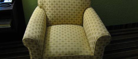 Un sillón amarillo con un estampado de diamantes frente a una pared verde.