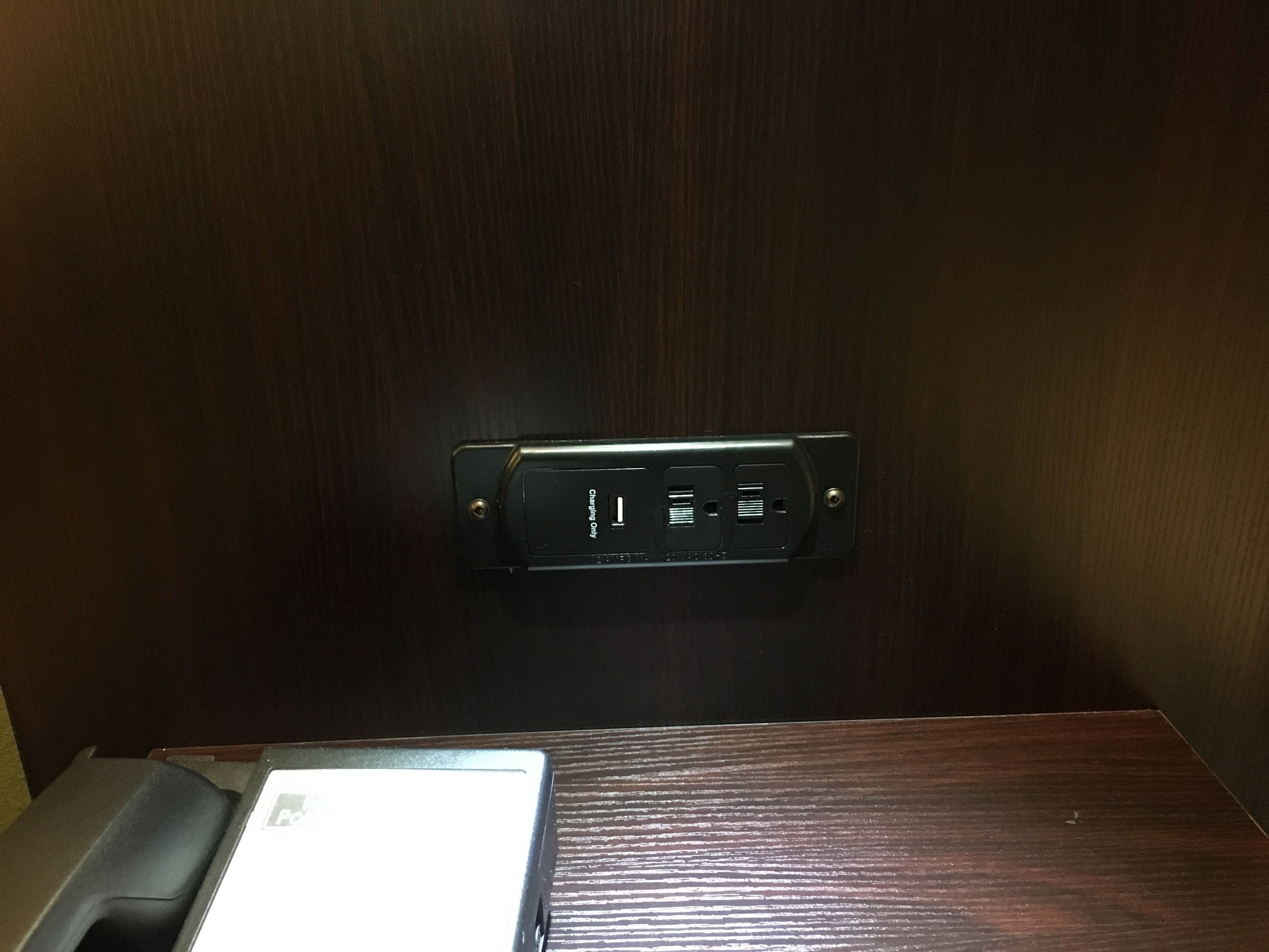 A wooden wall with a black charging station displaying a charging icon.