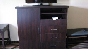 A dark wooden cabinet with a flat-screen TV on top, a drawer, and a shelf below. - Inn at Portland (Portland)