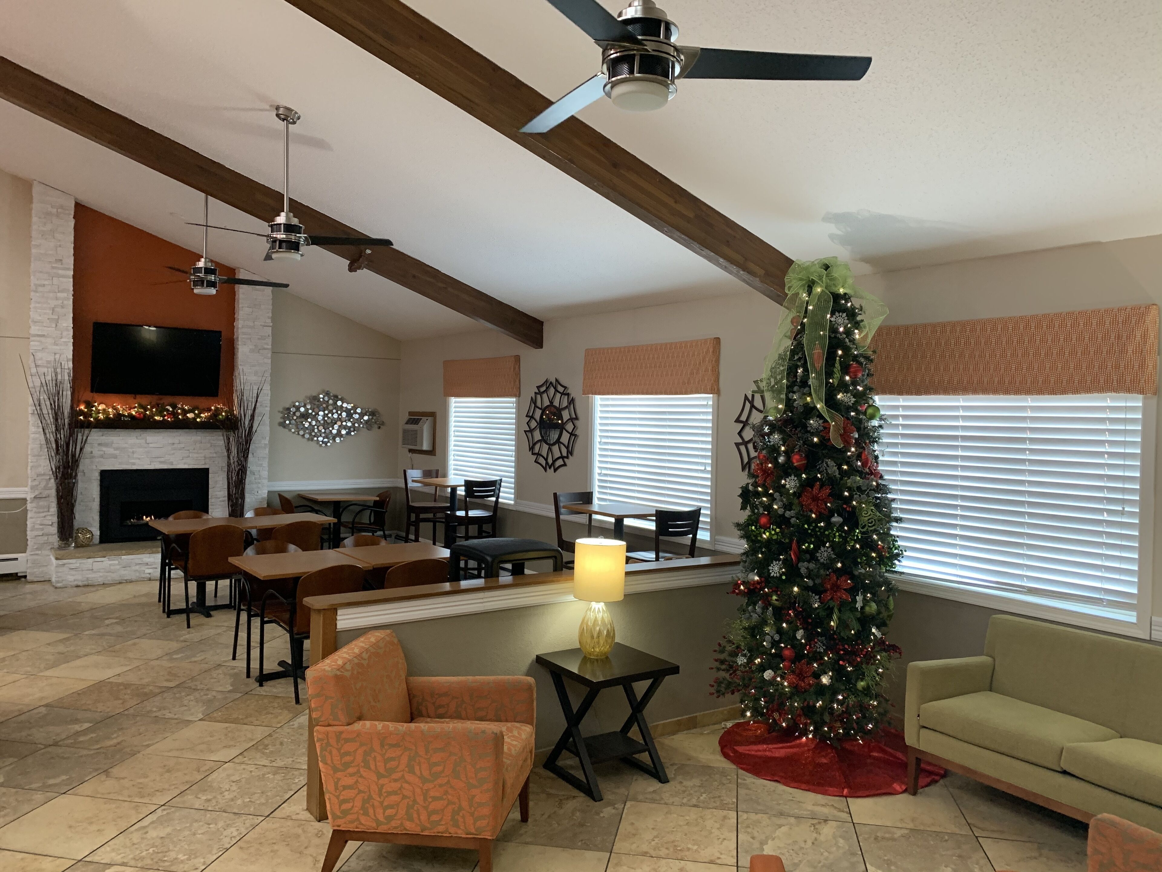 A spacious living room with a fireplace, a large Christmas tree, and a ceiling fan.