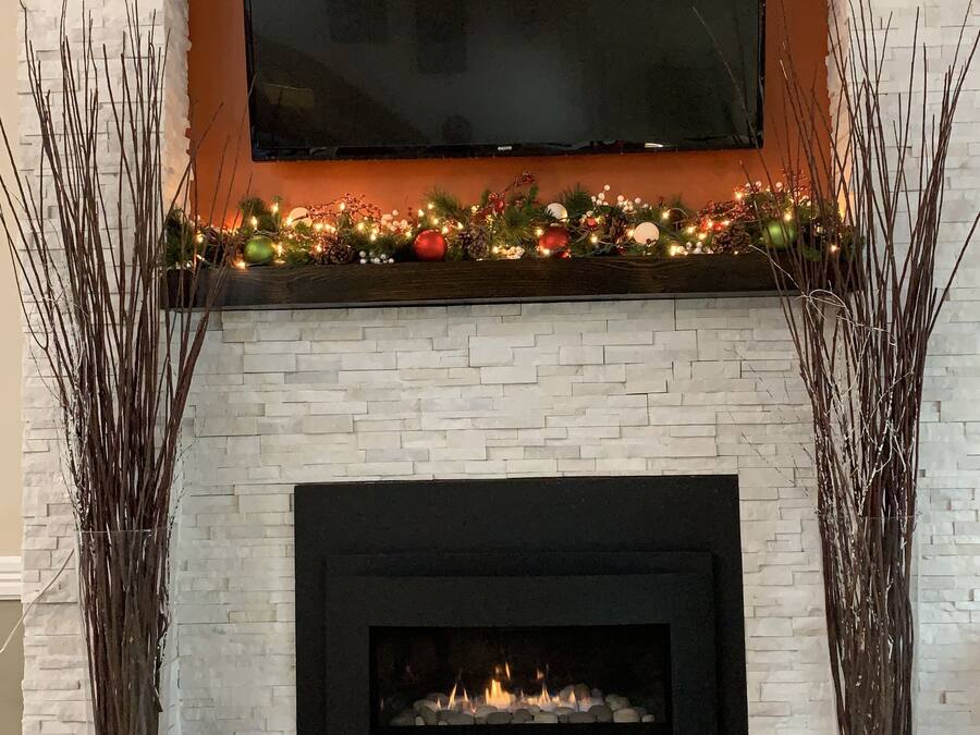 A fireplace with a TV mounted above it, surrounded by decorative foliage and ornaments.