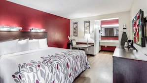 Een hotelkamer met een groot bed, een bureau, een stoel, een spiegel en een televisie.