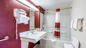 Un baño con un lavabo blanco, un espejo, una ducha con cortina a rayas rojas y blancas, y un inodoro blanco.