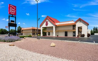 A Red Roof Inn with a two-story building, a parking lot, and a clear blue sky.