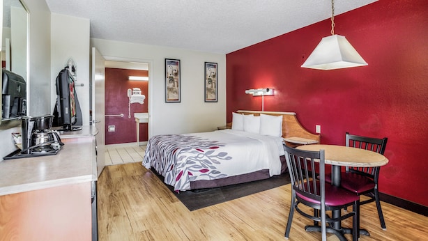 A hotel room with a bed, a dining table, chairs, a coffee machine, and a TV. - Red Roof Inn Gallup (Gallup)
