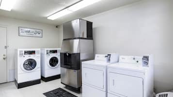 A laundry facility with a Whirlpool washer, a stacked washer and dryer unit, and a sign indicating self-service.