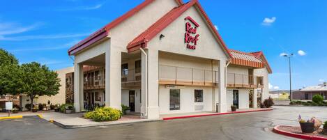 A Red Roof Inn with a red roof, multiple balconies, and a parking lot.