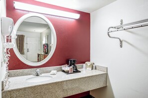 Un baño con encimera de granito, un lavabo blanco, un espejo, un perchero para toallas y una barandilla.