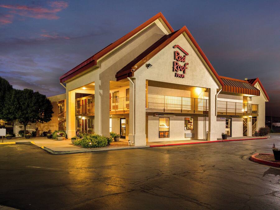 Un Red Roof Inn con una estructura de dos pisos, un porche cubierto y un estacionamiento.