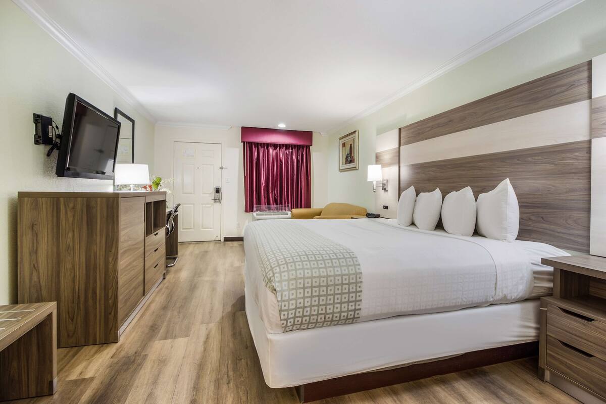 A hotel room with a bed, wooden furniture, a TV, and a door.