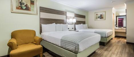 A hotel room with a large bed, a chair, and a painting on the wall.