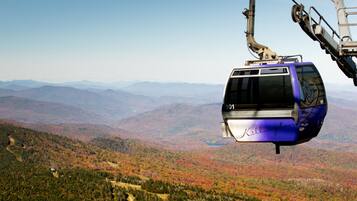 A cable car suspended over a mountainous landscape with autumn foliage.