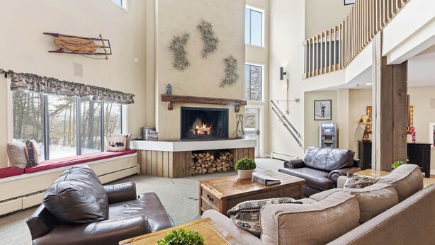 Un salón espacioso con chimenea, sofás de cuero, una mesa de centro de madera y vistas al exterior.