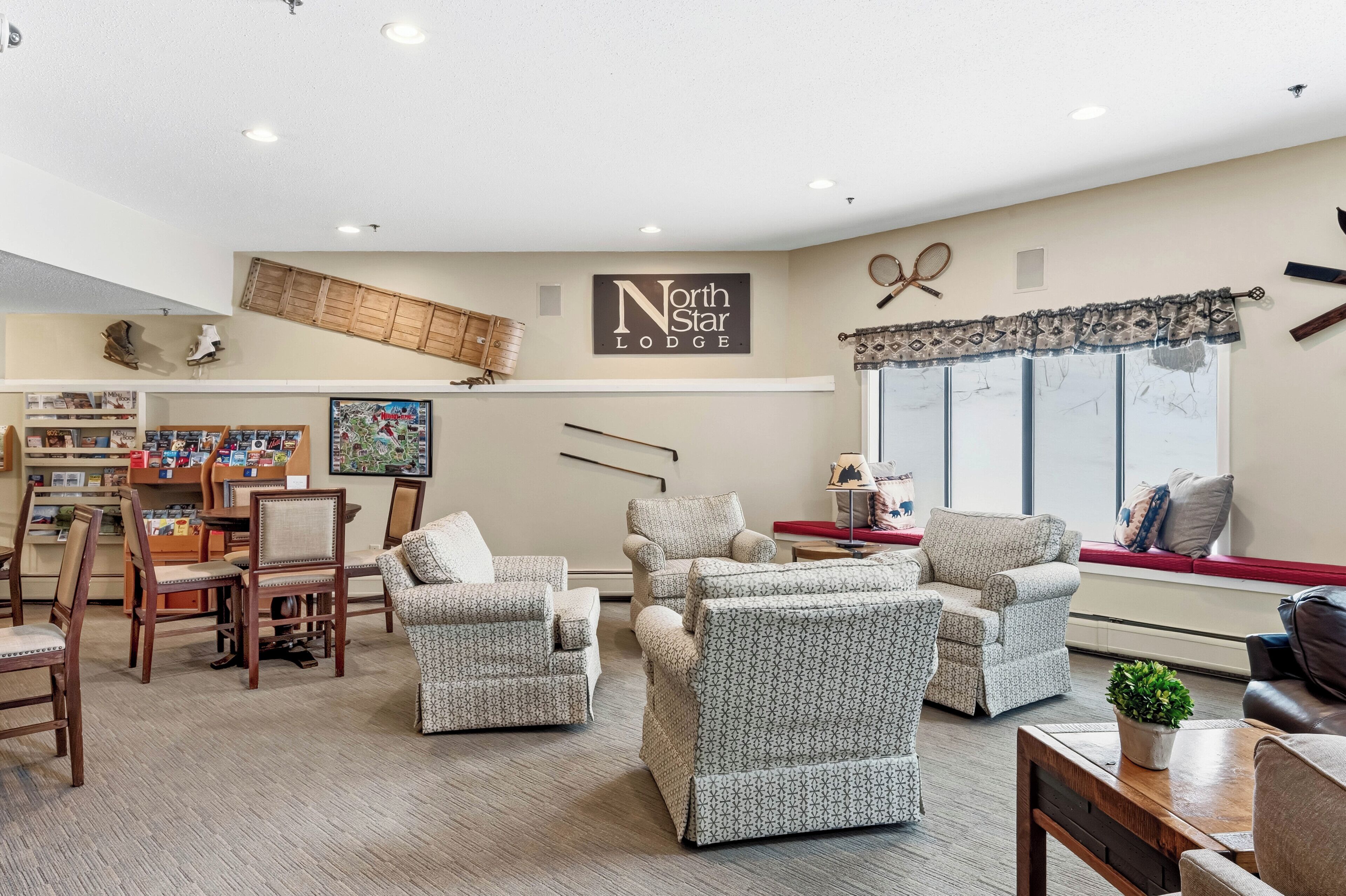 A cozy lounge area with patterned armchairs, a coffee table, and a fireplace. A sign reads 'North Star Lodge.'