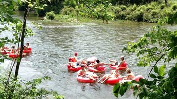 Des personnes flottent sur des radeaux rouges dans une rivière, entourée d’une végétation luxuriante.