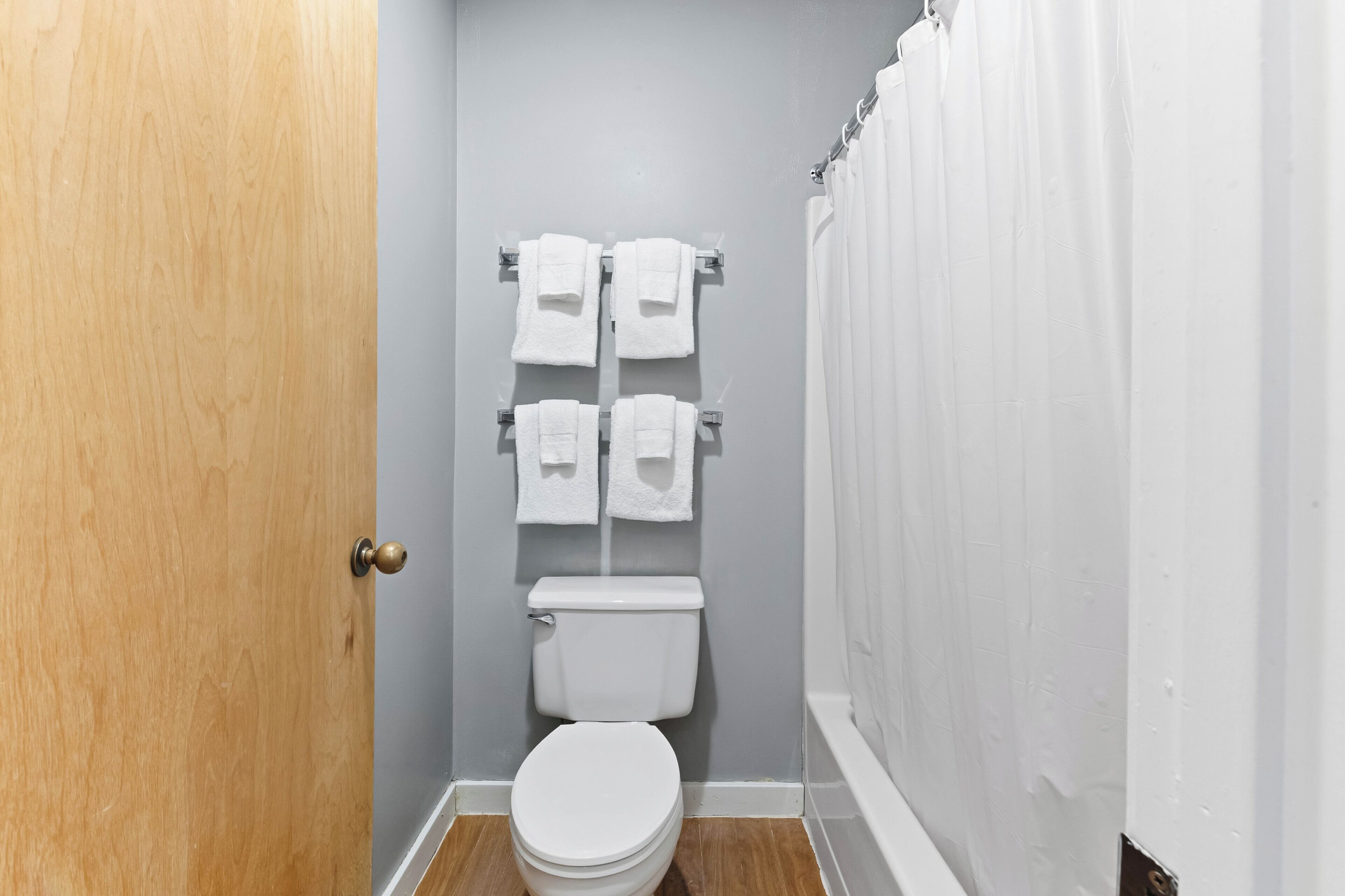 Een compacte badkamer met toilet, twee handdoekrekken en een douchegordijn.