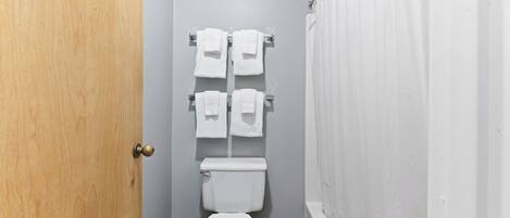 Un baño pequeño con inodoro, dos toalleros y cortina de ducha.