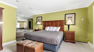 Un dormitorio con una cama grande, una mesita de noche de madera, una lámpara, un banco y un espejo.