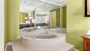 Un baño con una bañera independiente grande, un espejo y un tocador de madera.