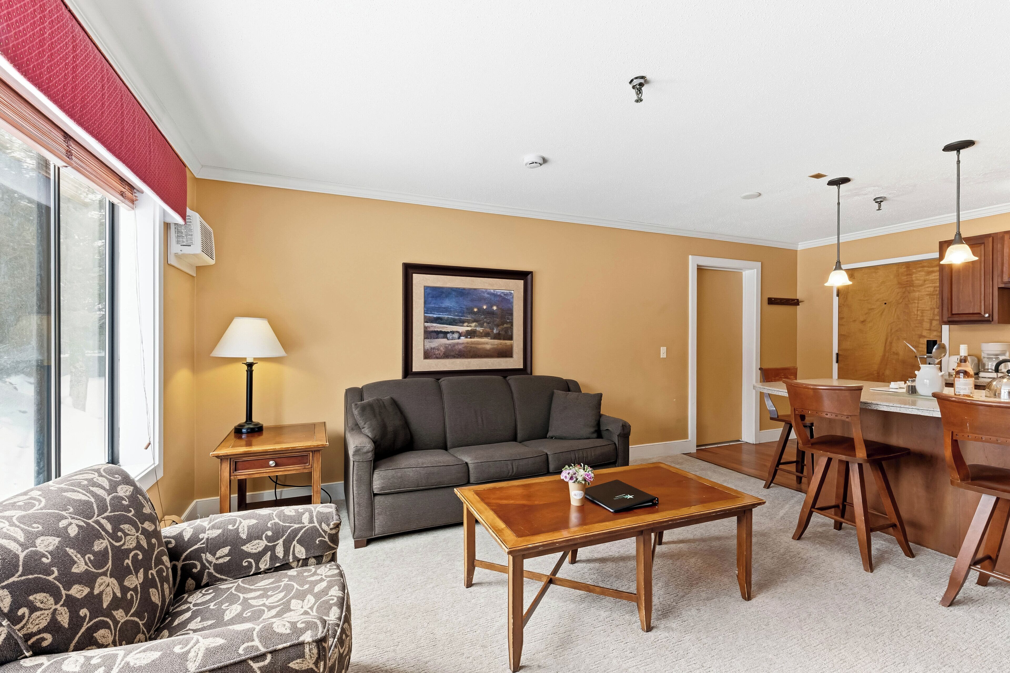 A living room with a sofa, a coffee table, a lamp, and a painting on the wall.