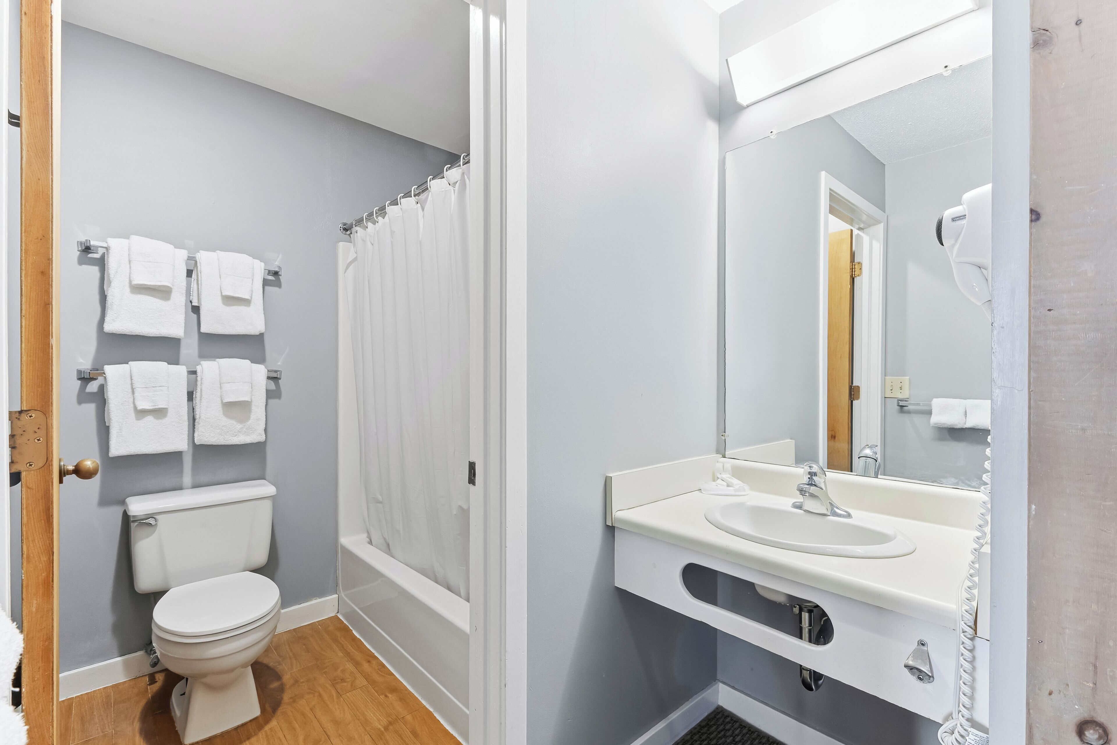 A bathroom with a toilet, shower curtain, sink, and mirror.