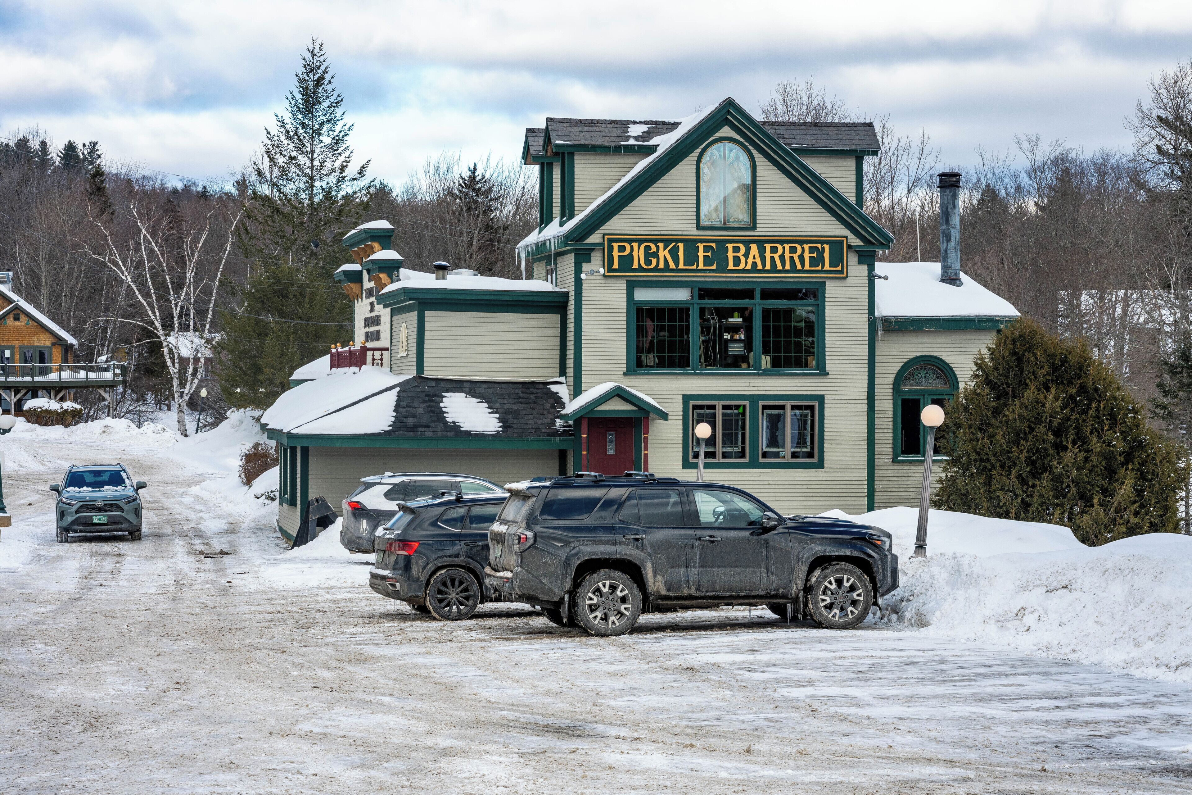 A building named 'Pickle Barrel' with a snow-covered roof, a chimney, and a signboard.