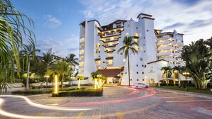 A multi-story hotel with a modern design, featuring balconies and a well-lit entrance.