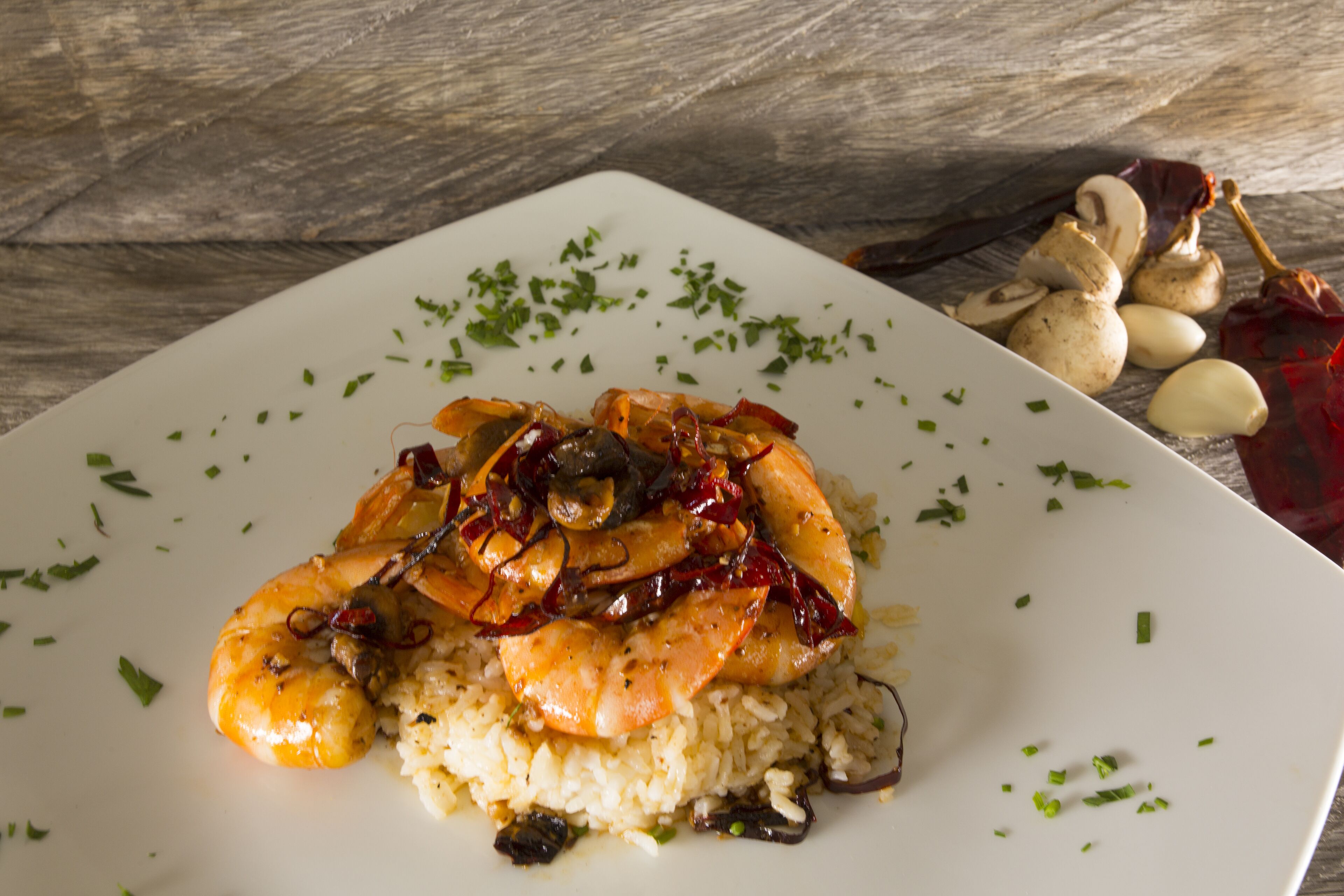 Un plato de camarones y arroz adornado con hierbas.