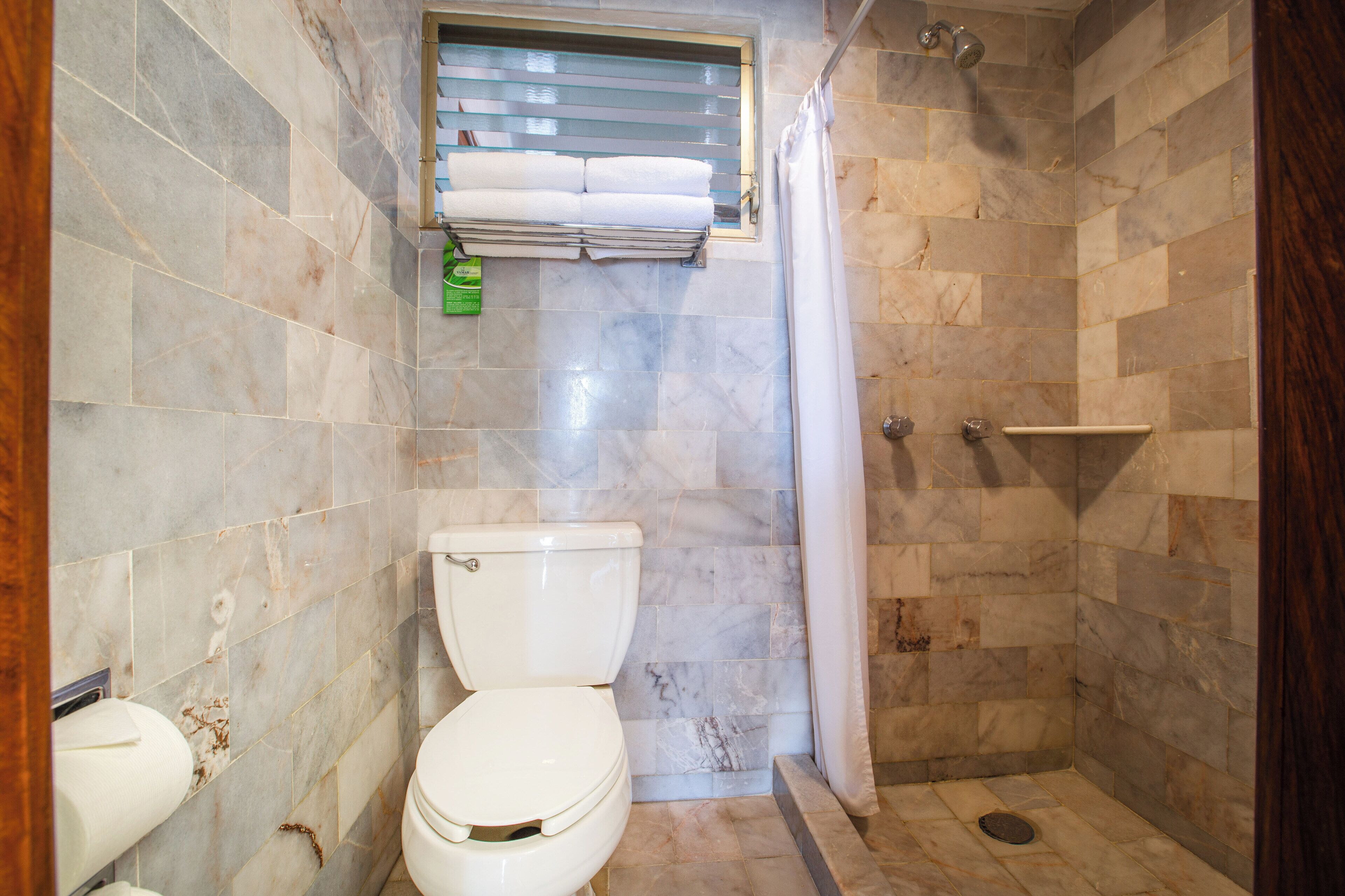 A bathroom with a toilet, shower, and a towel rack.