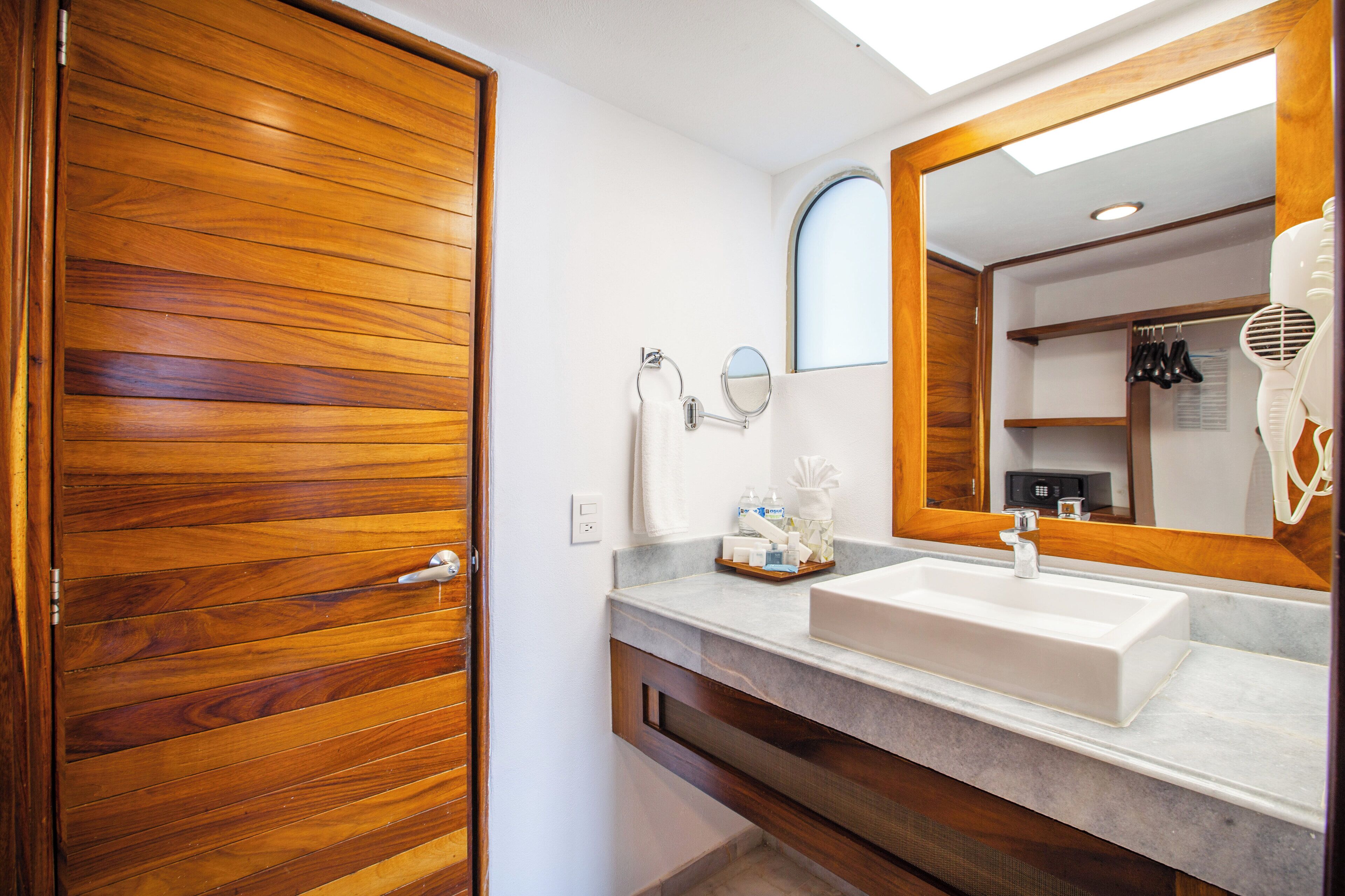 Un baño con puerta de madera, un lavabo con espejo y un secador en la encimera.
