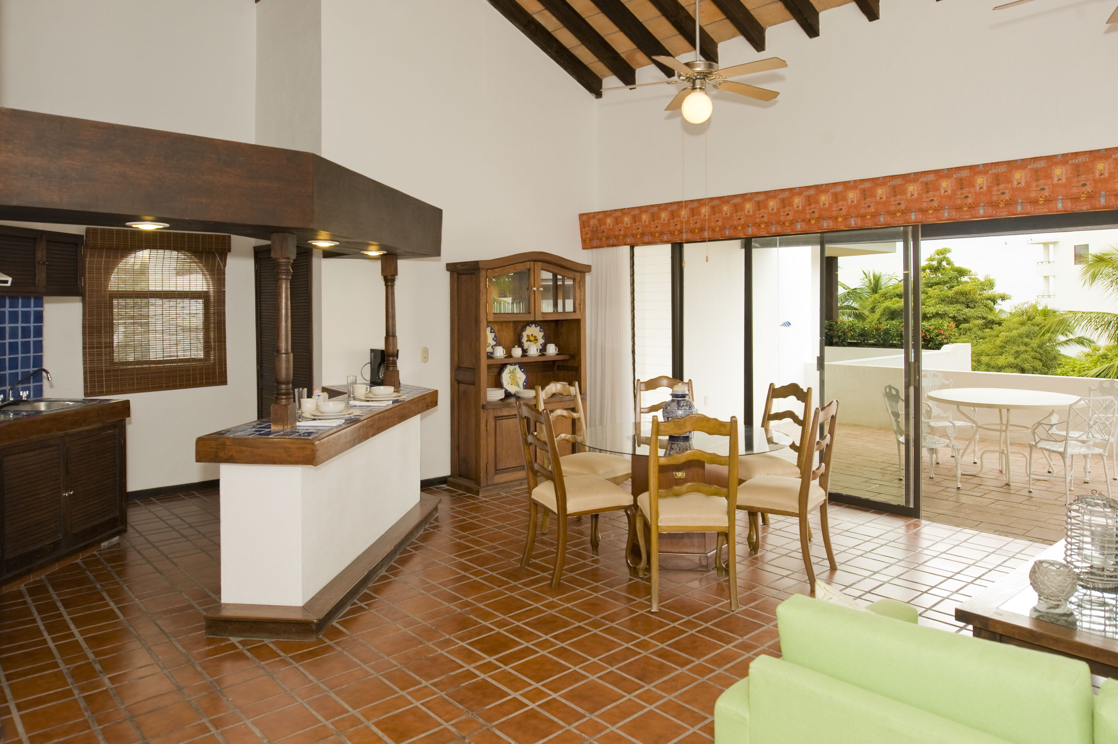 A spacious kitchen with a dining area, a wooden cabinet, and a ceiling fan.