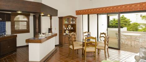 A spacious kitchen with a dining area, a wooden cabinet, and a ceiling fan.
