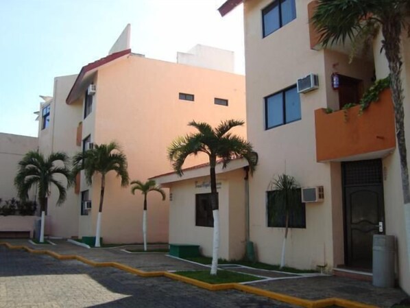 Una hilera de edificios modernos con balcones, palmeras y un sendero pavimentado.