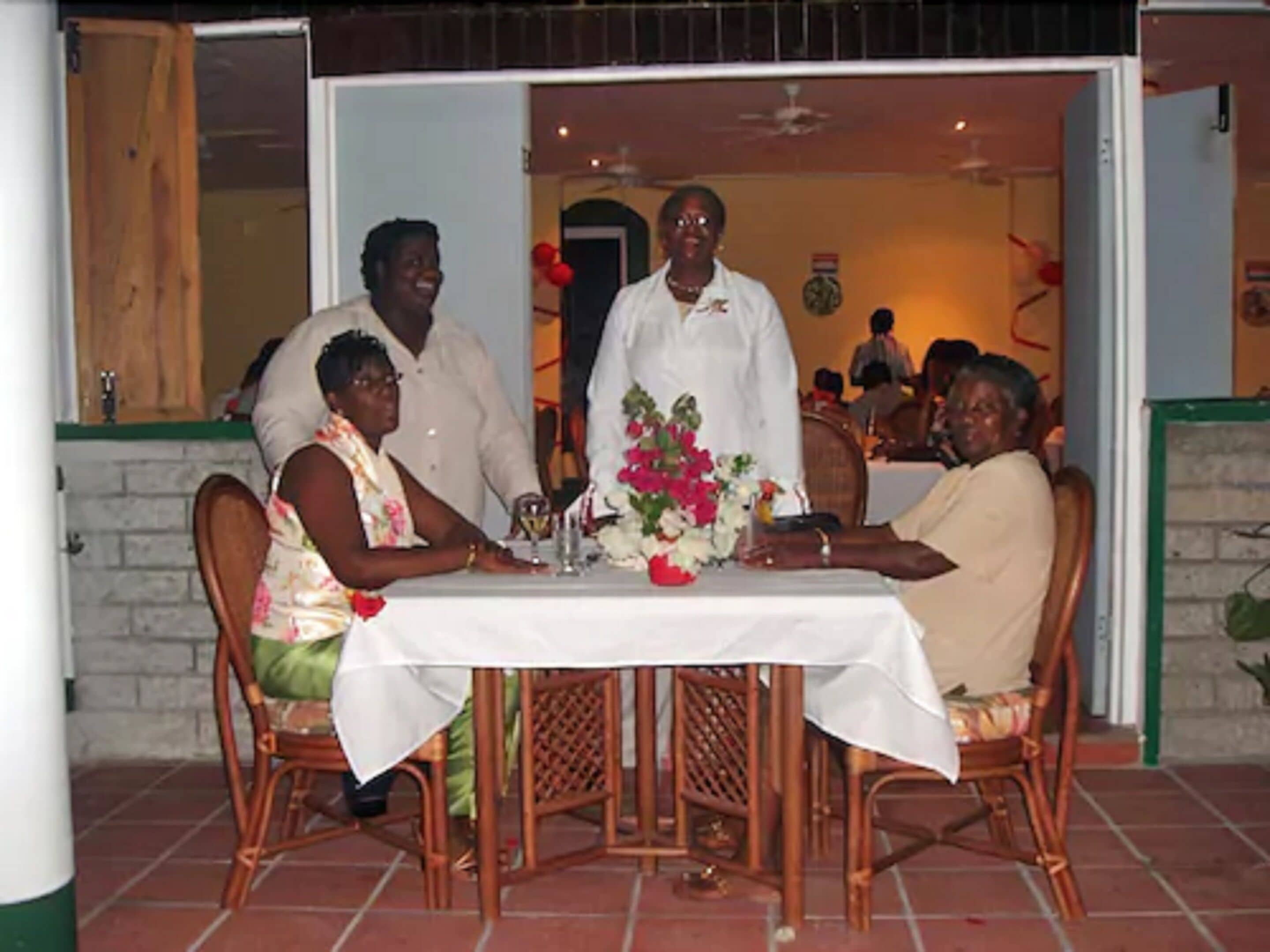 Un coin repas avec une table dressée pour quatre personnes, entourée de chaises en osier.
