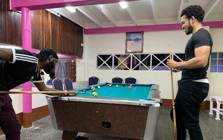 A pool table in a room with a wooden ceiling and a window with a view of a landscape.