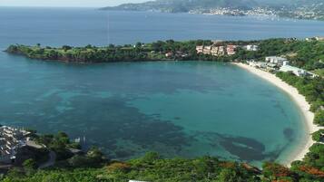 A coastal area with a beach, clear waters, and buildings along the shore.
