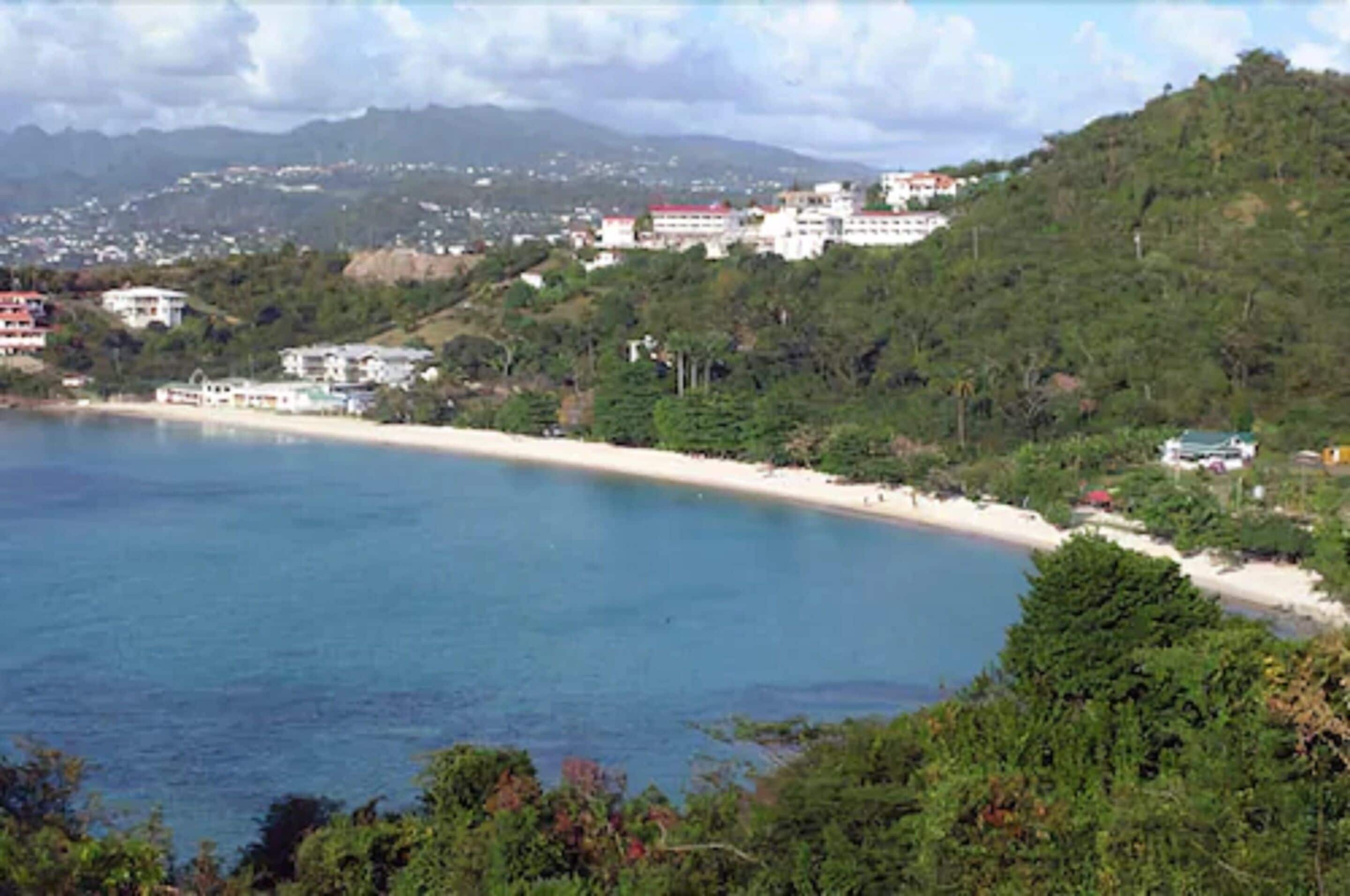 Eine Küstenlandschaft mit Strand, Gebäuden und Hügeln.