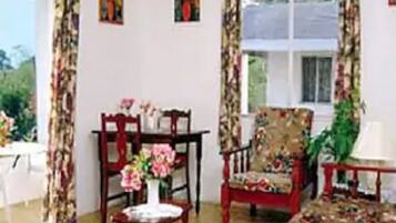A room with a wooden table, a floral armchair, and a window with curtains.