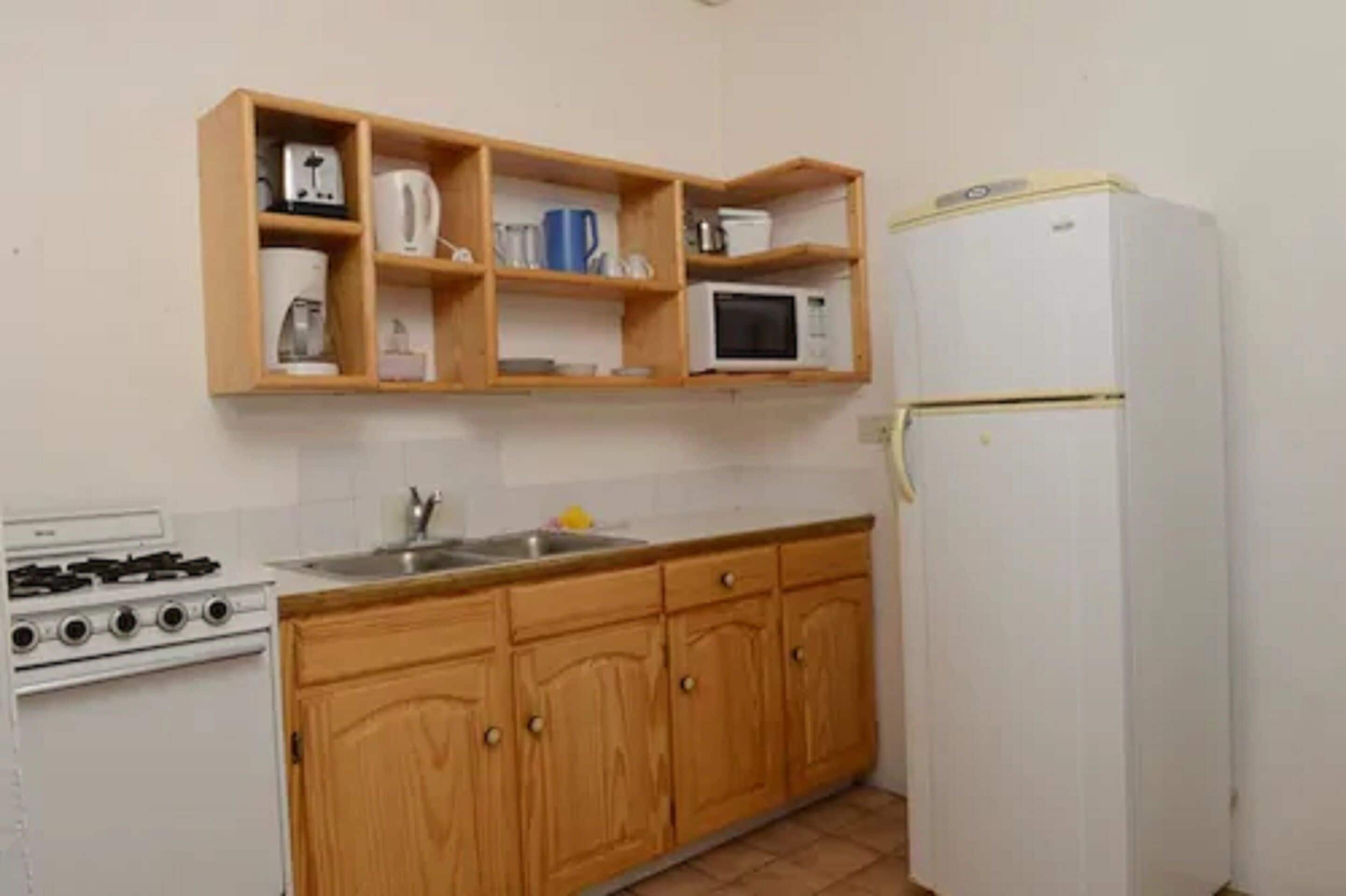 Una cocina compacta con armarios de madera, una estufa blanca, un microondas y un refrigerador.
